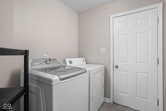 clothes washing area featuring laundry area, light tile patterned flooring, and washing machine and clothes dryer