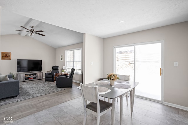 dining space featuring lofted ceiling with beams, light wood-style floors, baseboards, and a textured ceiling