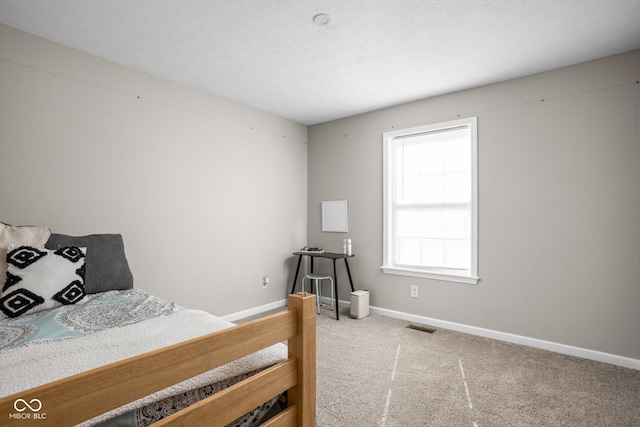 bedroom featuring a textured ceiling, carpet flooring, visible vents, and baseboards