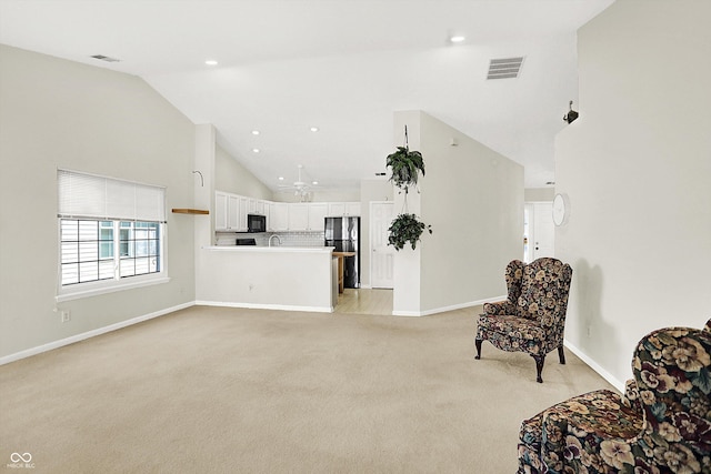 unfurnished living room with high vaulted ceiling, baseboards, visible vents, and light colored carpet