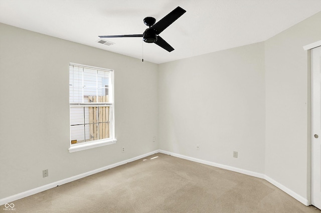 carpeted spare room with a ceiling fan, visible vents, and baseboards