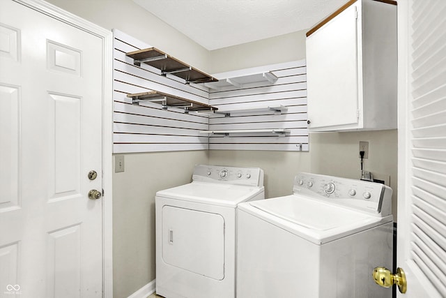 laundry room featuring a textured ceiling, cabinet space, and washer and dryer