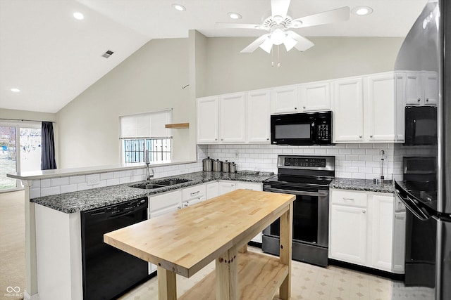 kitchen with white cabinets, a sink, plenty of natural light, a peninsula, and black appliances