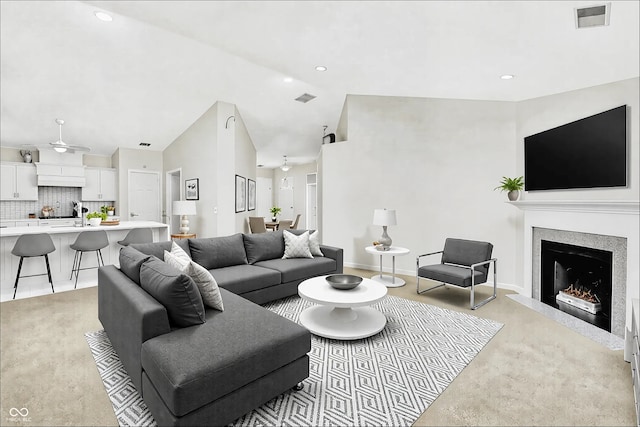 living room with a warm lit fireplace, visible vents, ceiling fan, and baseboards