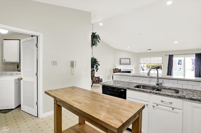 kitchen with a fireplace, white cabinetry, a sink, washer / dryer, and dishwasher