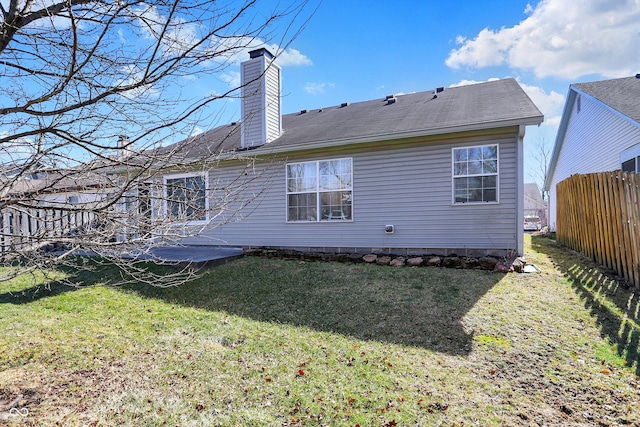 rear view of house with a chimney, fence, and a yard