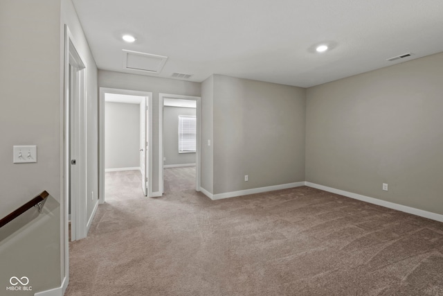 carpeted empty room featuring attic access, visible vents, and baseboards