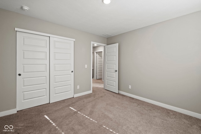 unfurnished bedroom featuring carpet floors, visible vents, baseboards, and a closet