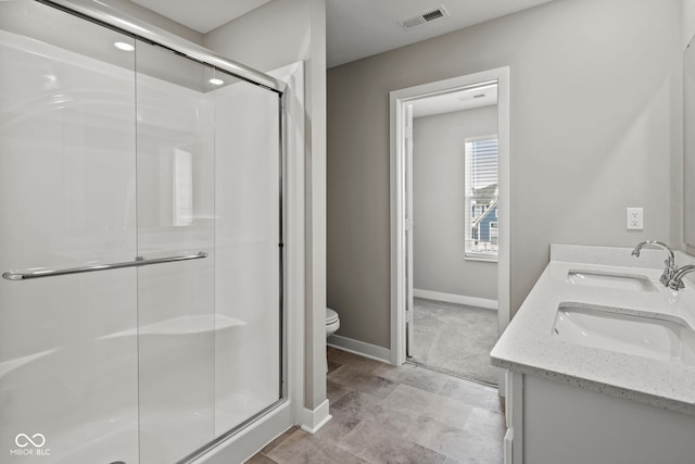 bathroom featuring visible vents, toilet, a stall shower, a sink, and baseboards