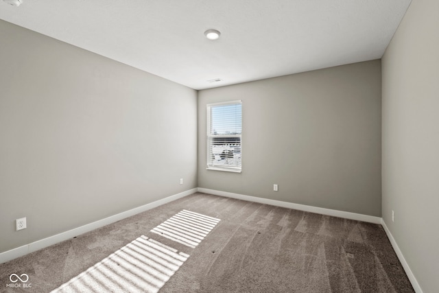 unfurnished room featuring carpet floors, visible vents, and baseboards