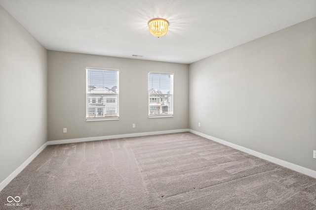 spare room featuring carpet floors and baseboards