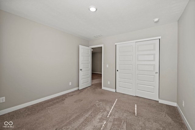 unfurnished bedroom with carpet, a closet, and baseboards