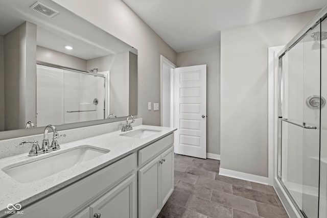 bathroom with visible vents, a sink, a shower stall, and baseboards