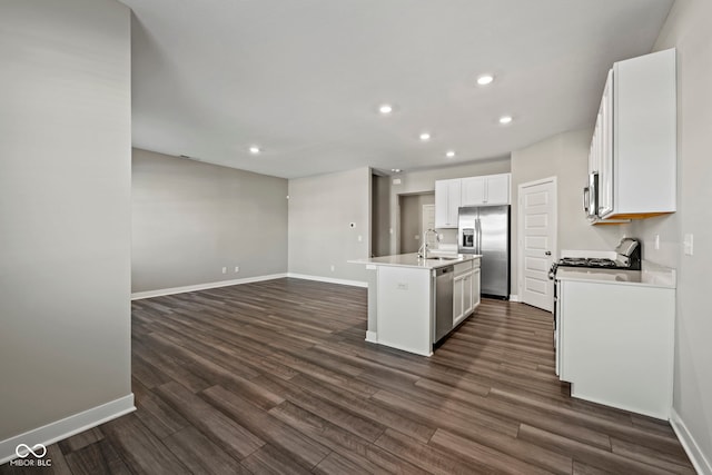 kitchen with dark wood-style flooring, stainless steel appliances, open floor plan, a kitchen island with sink, and a sink