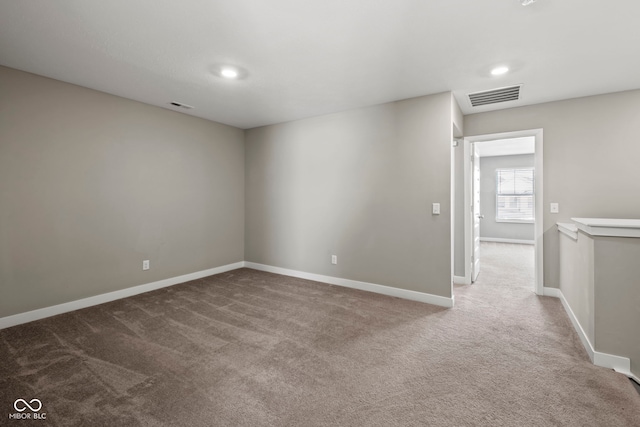 unfurnished room with carpet flooring, visible vents, and baseboards