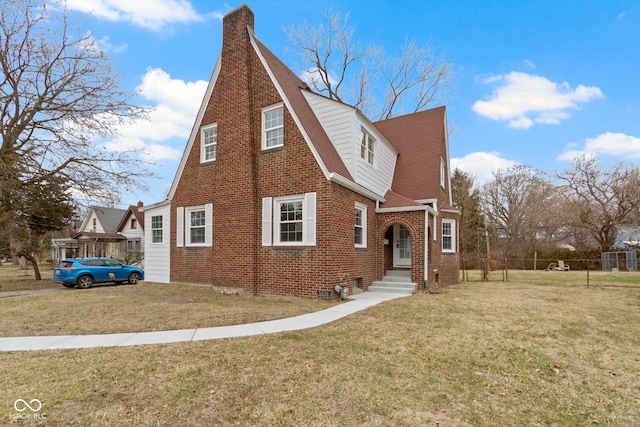 view of front of property with brick siding, a front lawn, a chimney, and fence