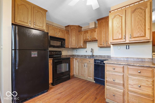 kitchen featuring light countertops, light wood-style flooring, a ceiling fan, a sink, and black appliances