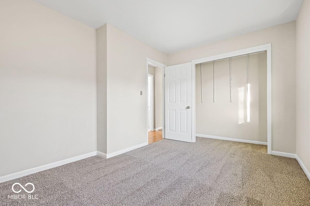 unfurnished bedroom with carpet, a closet, and baseboards