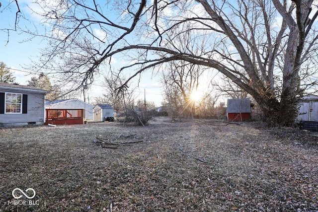 view of yard featuring a deck, a shed, and an outbuilding