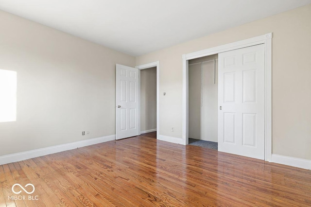 unfurnished bedroom with light wood-type flooring, baseboards, and a closet