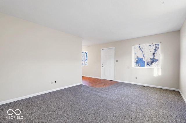 empty room featuring carpet, visible vents, and baseboards