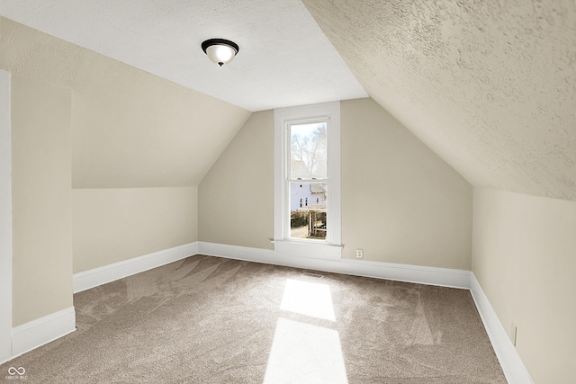 bonus room with lofted ceiling, carpet flooring, a textured ceiling, and baseboards