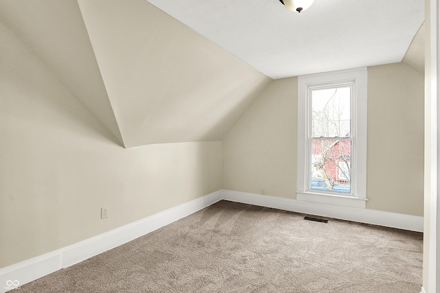 additional living space with lofted ceiling, carpet flooring, visible vents, and baseboards