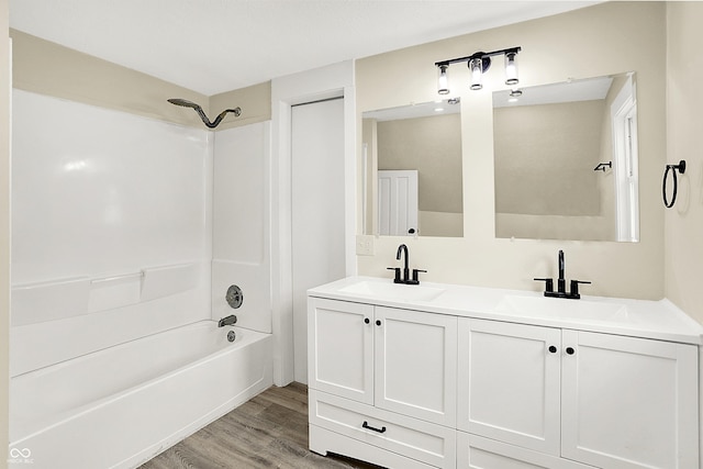 bathroom featuring  shower combination, double vanity, a sink, and wood finished floors