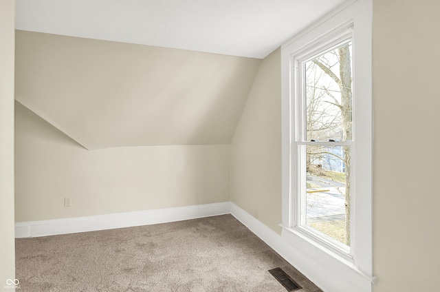 bonus room featuring lofted ceiling, carpet flooring, visible vents, and baseboards