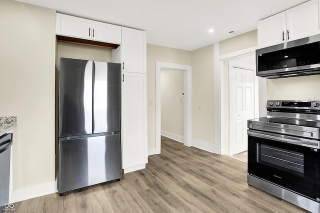 kitchen with white cabinets, light wood-type flooring, baseboards, and stainless steel appliances