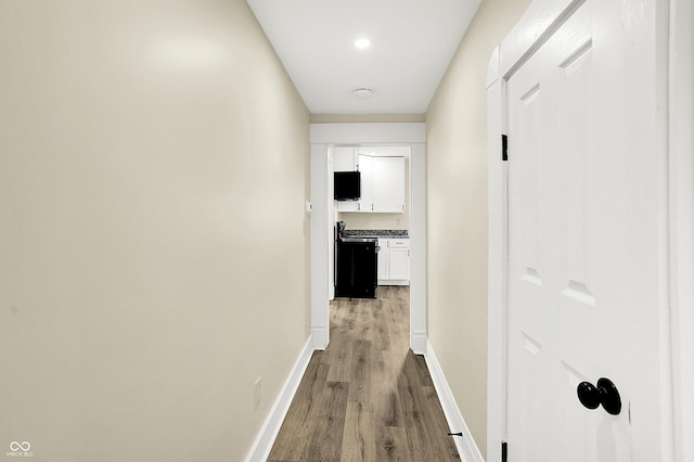 corridor featuring baseboards and wood finished floors