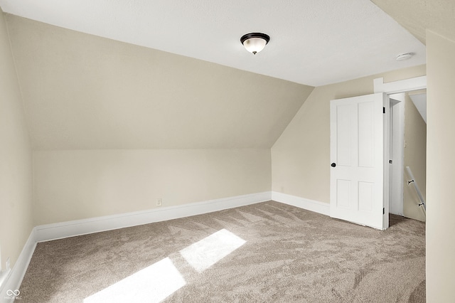 additional living space with baseboards, vaulted ceiling, and carpet flooring