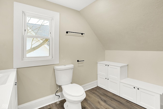 bathroom with lofted ceiling, a textured ceiling, toilet, wood finished floors, and baseboards