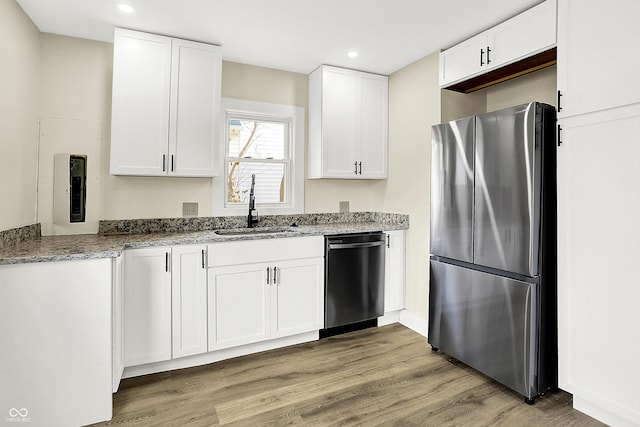 kitchen featuring light wood-style flooring, freestanding refrigerator, white cabinetry, a sink, and dishwashing machine