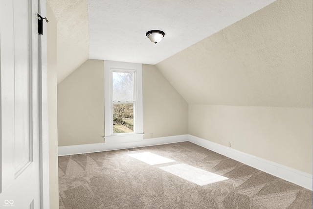 bonus room featuring a textured ceiling, carpet, lofted ceiling, and baseboards