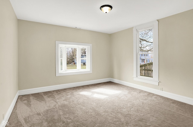 carpeted spare room with visible vents and baseboards