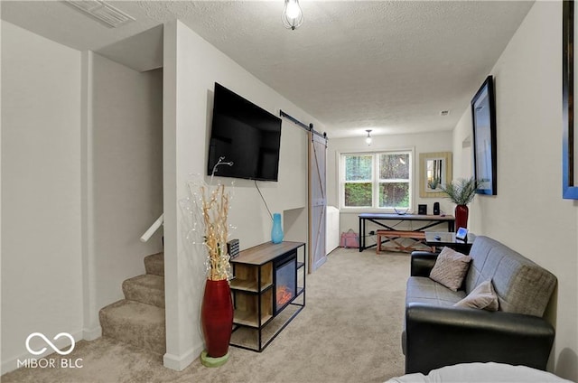 living area with visible vents, stairway, a barn door, light carpet, and a textured ceiling