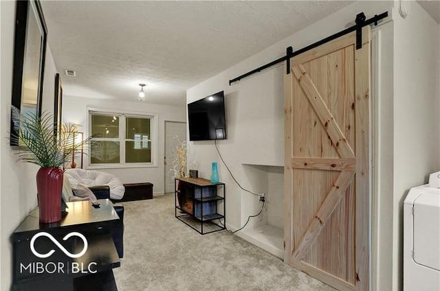 living room featuring washer / dryer, a barn door, visible vents, a textured ceiling, and carpet floors