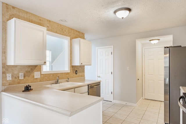 kitchen featuring light tile patterned floors, a sink, decorative backsplash, appliances with stainless steel finishes, and white cabinetry