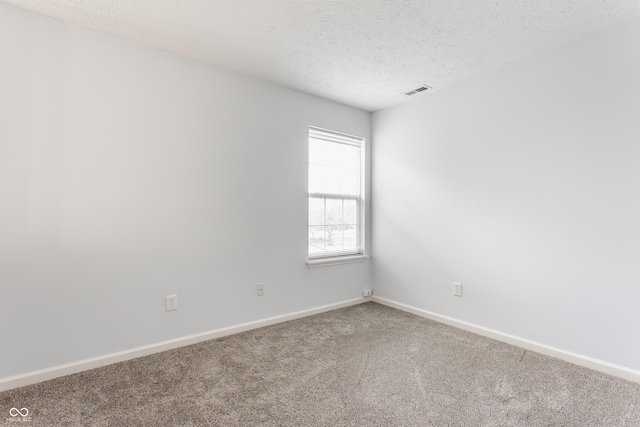 carpeted spare room with visible vents, baseboards, and a textured ceiling