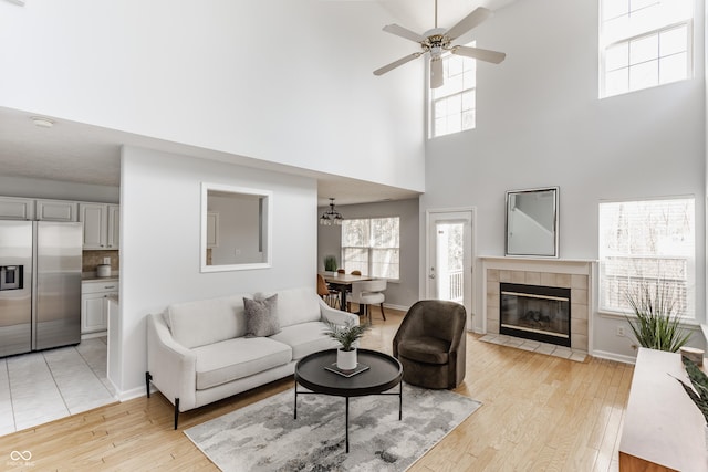 living room with a ceiling fan, light wood-style floors, baseboards, and a fireplace