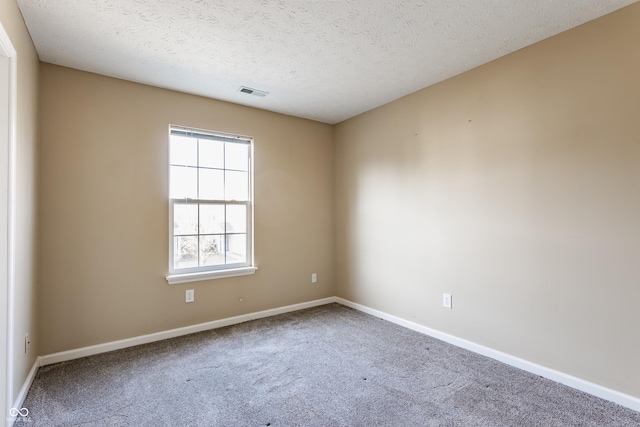 empty room featuring visible vents, baseboards, carpet, and a textured ceiling