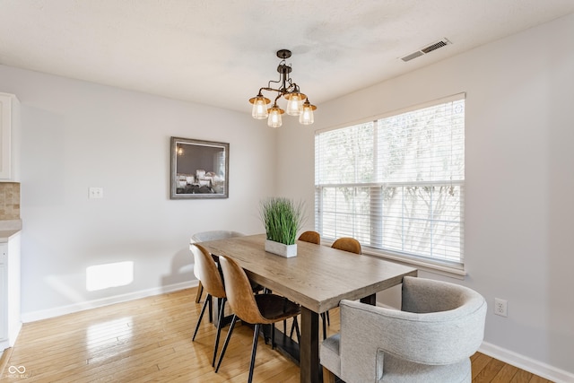 dining room with visible vents, baseboards, light wood-style flooring, and a chandelier