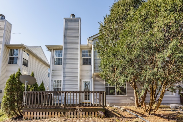 back of house with a wooden deck and a chimney