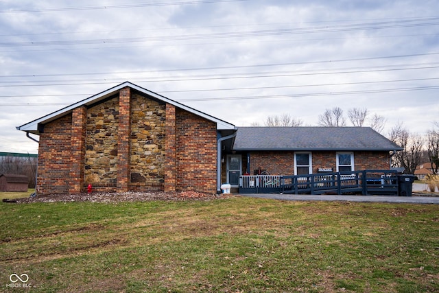 exterior space with brick siding, a front yard, and a shingled roof