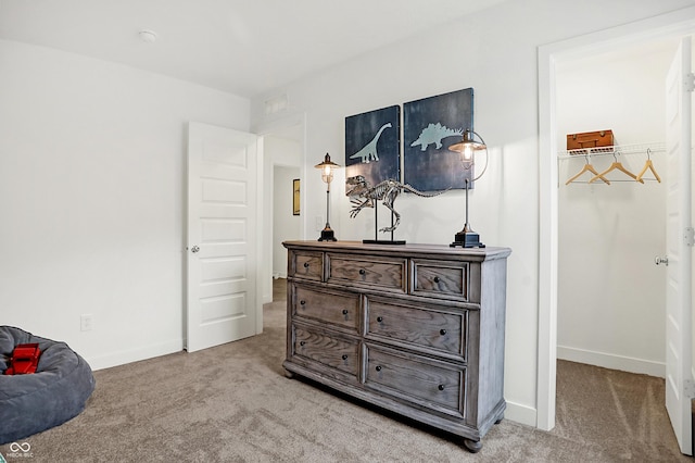 bedroom with carpet floors, a spacious closet, and baseboards