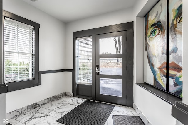 doorway to outside with marble finish floor and baseboards