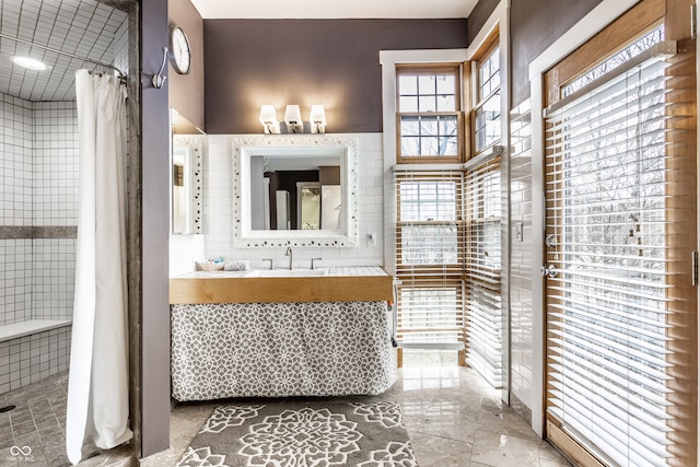 full bathroom with curtained shower, vanity, and tile walls