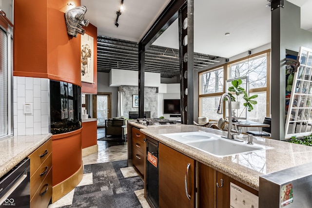 kitchen featuring a sink, stone tile flooring, light countertops, decorative backsplash, and dishwasher