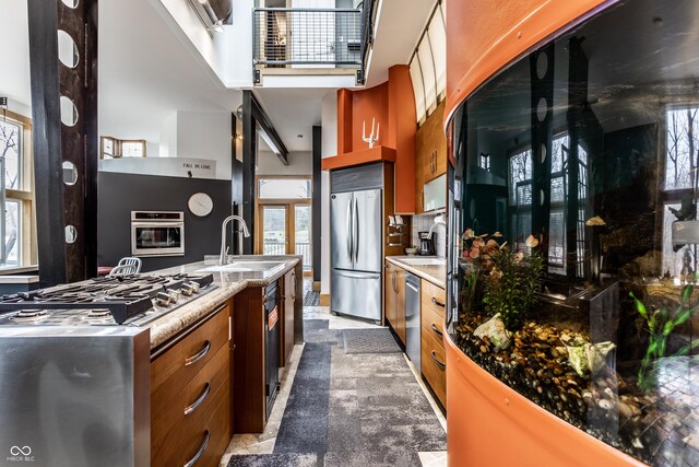 kitchen with a sink, stainless steel appliances, light countertops, stone finish floor, and brown cabinets